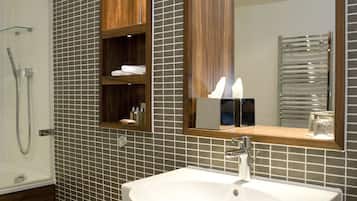 A bathroom with a white toilet, a sink with a mirror above it, and a shower area.