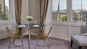 A dining area with a marble table, gold chairs, and a vase of white flowers. - Fraser Suites Edinburgh (Edinburgh)