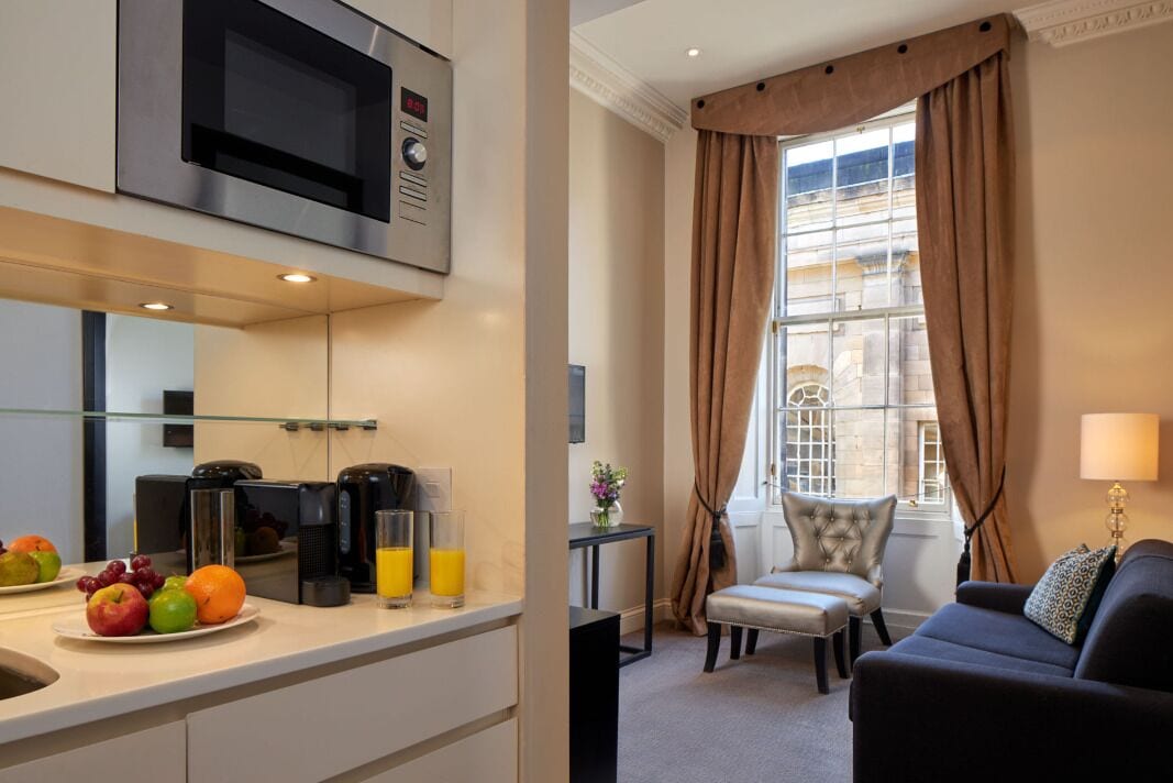 Een moderne hotelkamer met kitchenette, een eethoek en een zithoek met uitzicht op de stad.