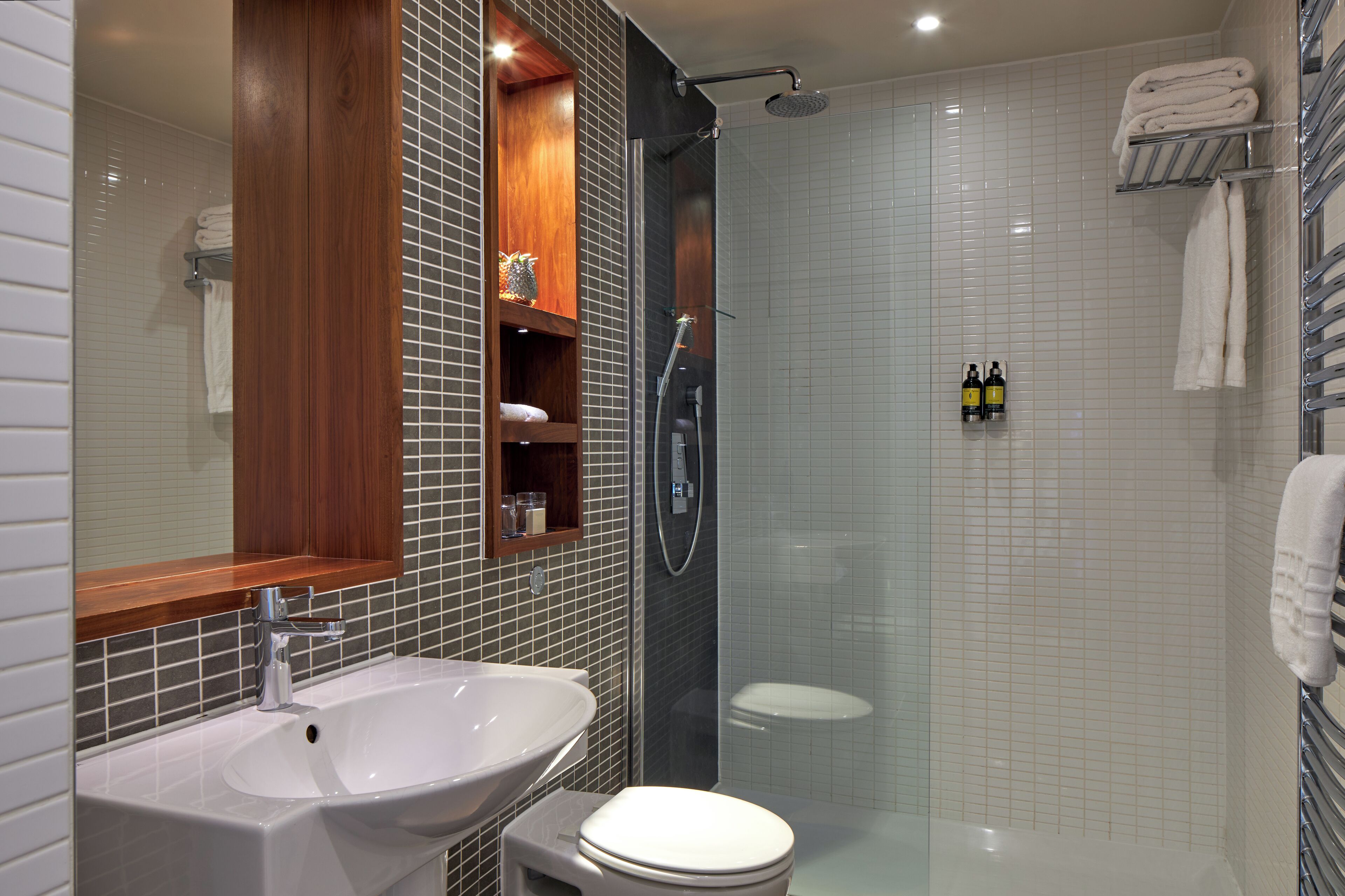 Un bagno moderno con un lavandino bianco, un water e una doccia.