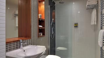 Un bagno moderno con un lavandino bianco, un water e una doccia.