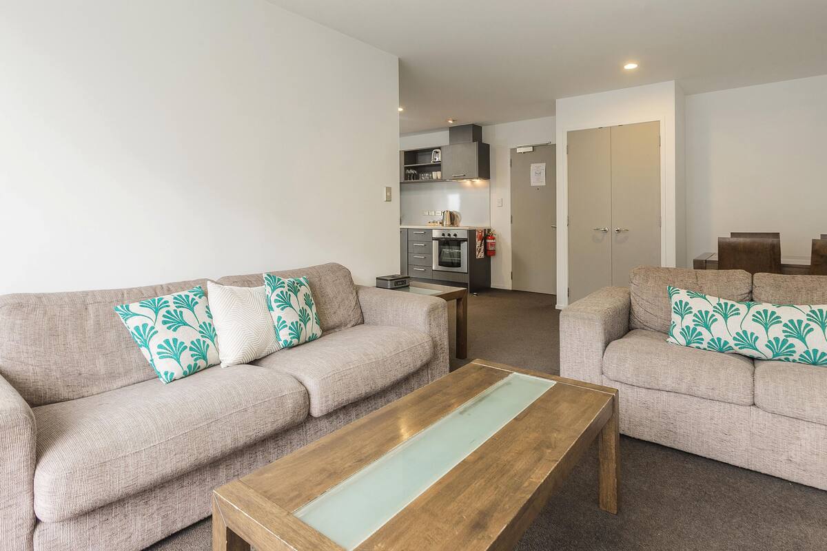 A living room with two sofas, a coffee table, and a kitchen in the background.