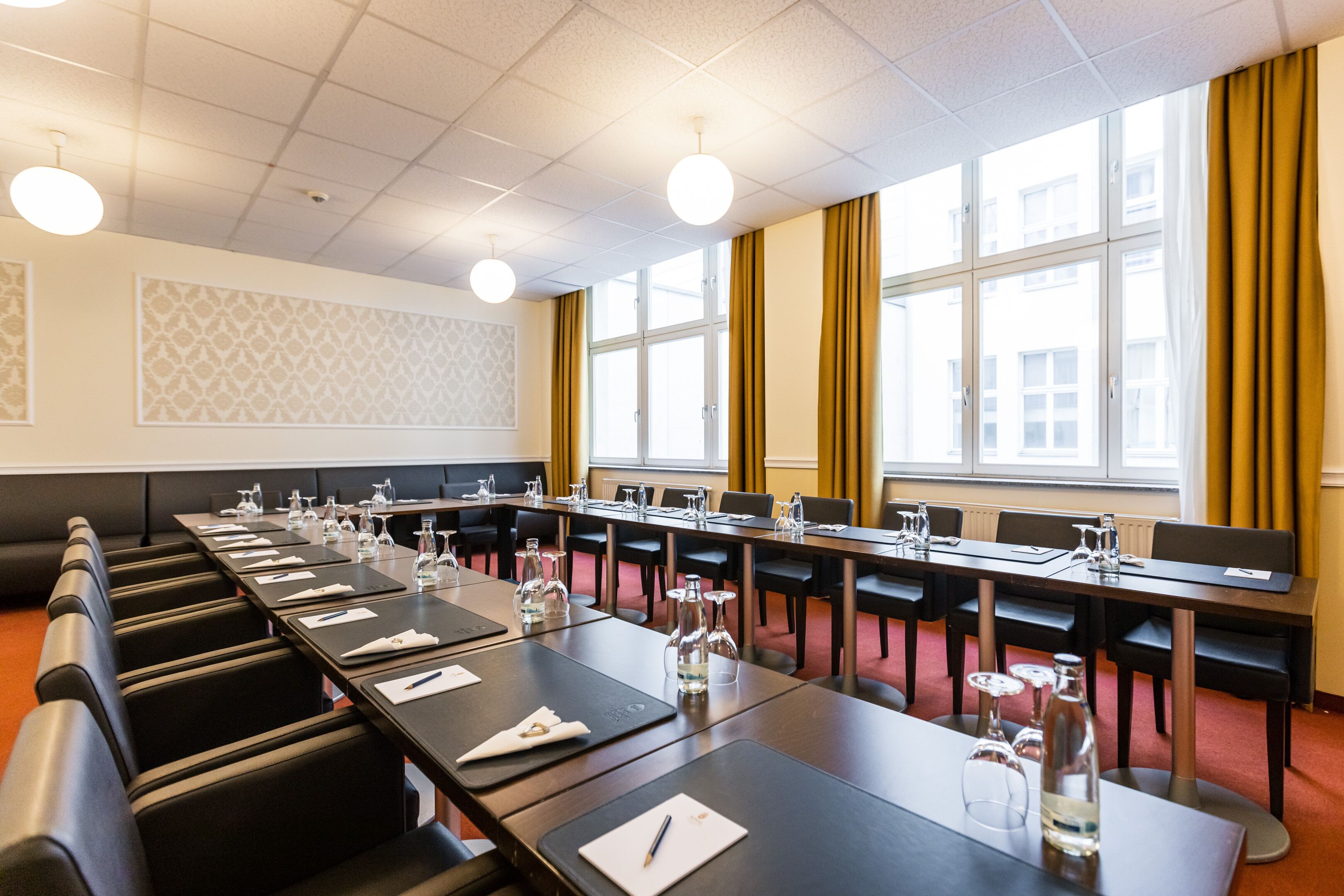 A conference room with long tables, chairs, and a large window with curtains.