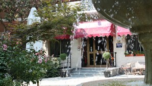 Entrada d'hotel amb una tenda vermella, una font i seients a l'exterior.