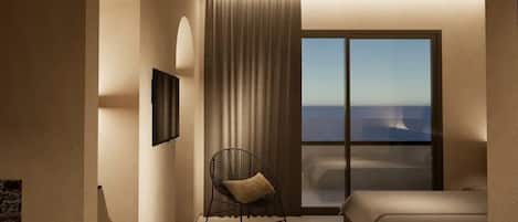 A bedroom with a large window, a bed, a chair, and a wall-mounted picture.