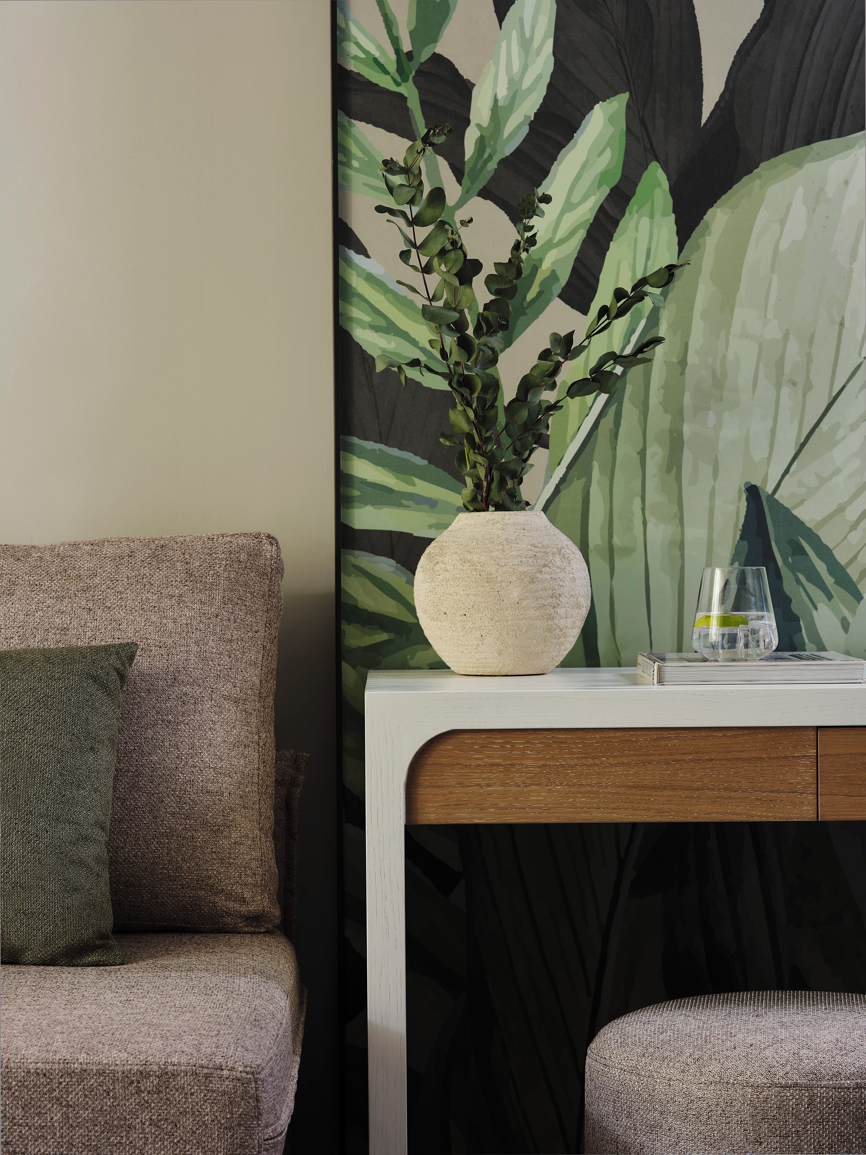 A living room with a sofa, a coffee table, and a painting of foliage.