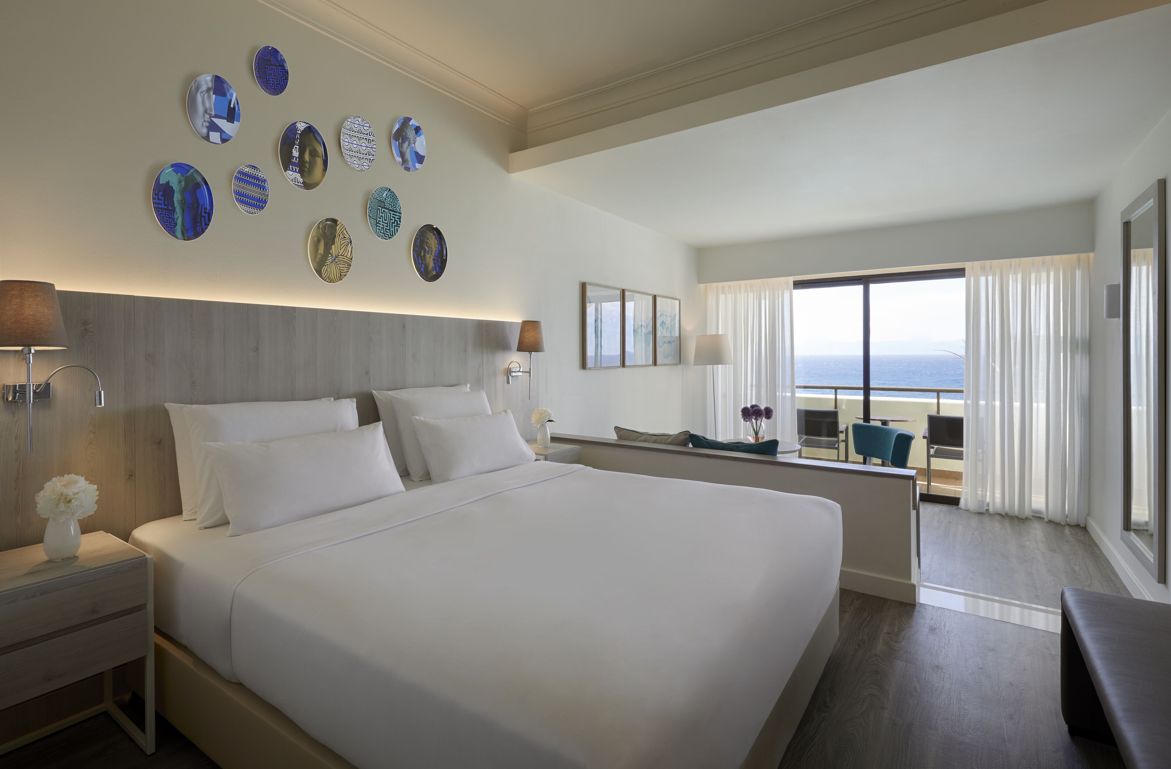 A hotel room with a large bed, a desk, and a view of the ocean.