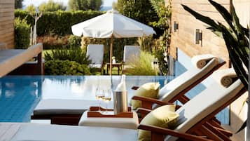 Zona de piscina con sillones de descanso, una sombrilla y una botella de champán.