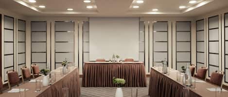 A conference room with a long table, chairs, and a projector screen.