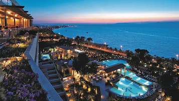 Relax by the infinity pool overlooking the ocean, surrounded by lounge chairs and umbrellas in a serene outdoor space.