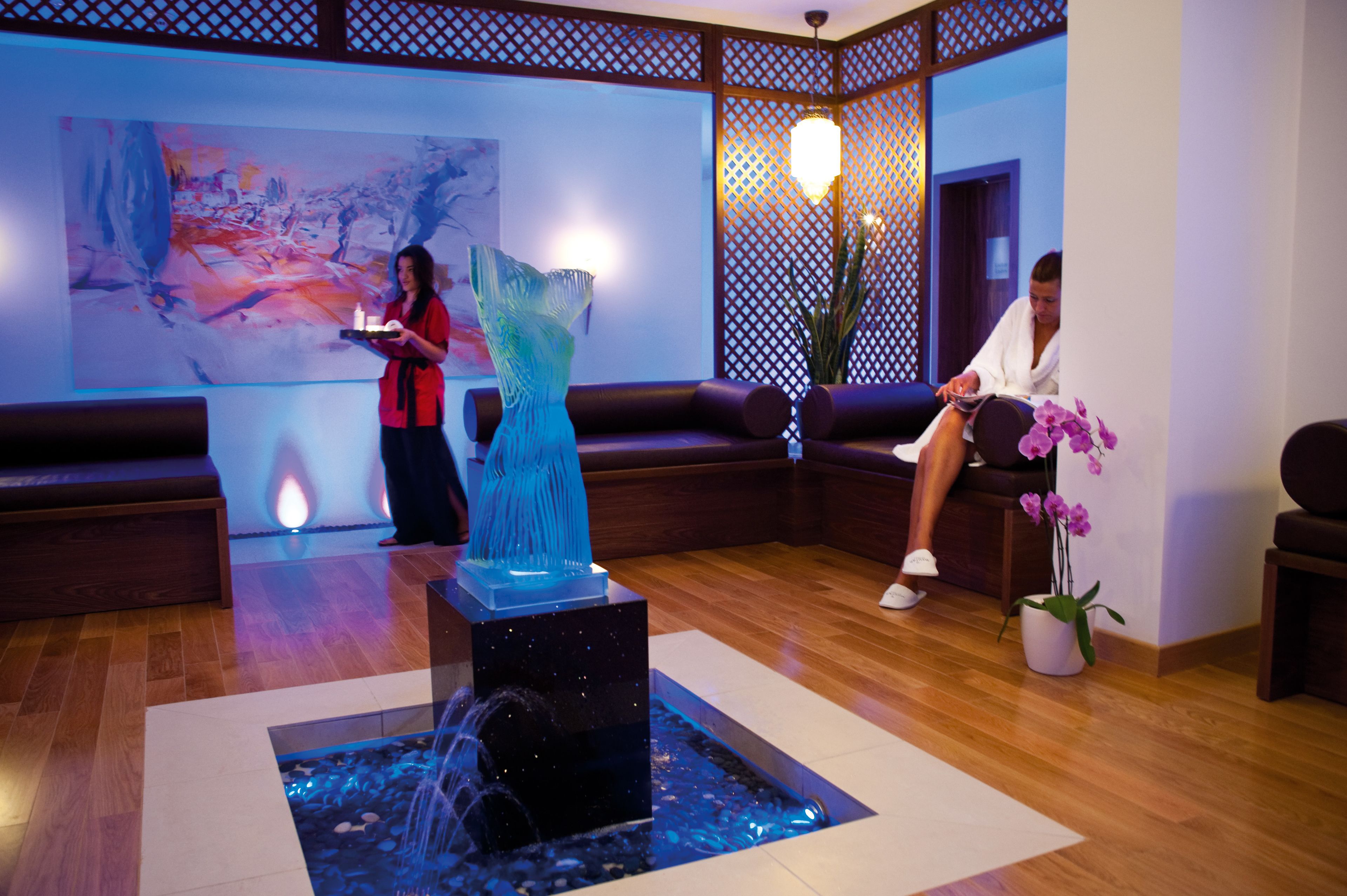 A modern lobby with a water feature, seating areas, and a large abstract painting.