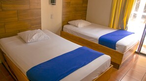 Two single beds with wooden headboards, white bedding, and blue bedspreads in a room with wooden panel walls and a tiled floor. - Hotel Bahia Del Sol (La Herradura)