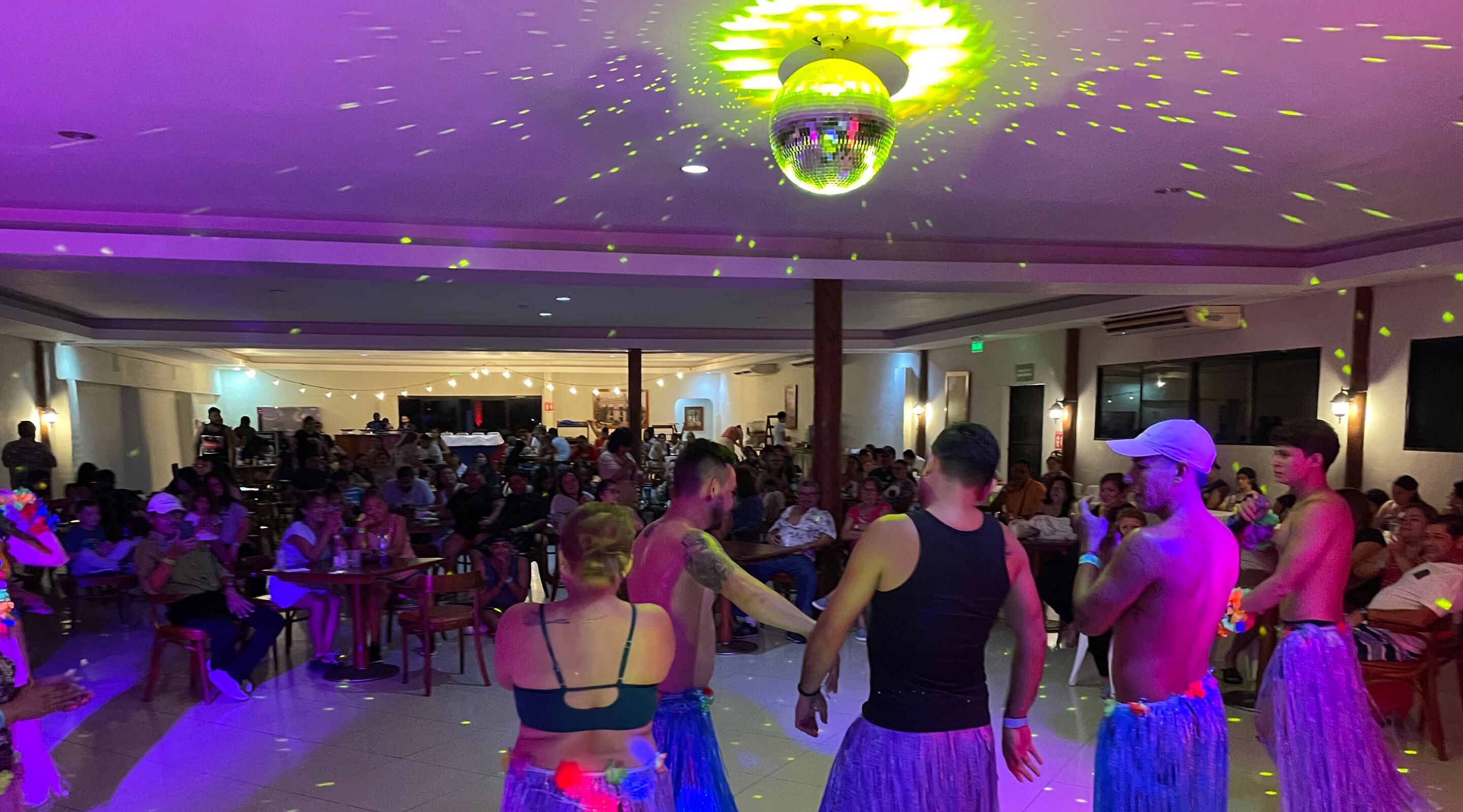 Un amplio espacio interior con una bola de discoteca, mesas y sillas dispuestas para un evento social.