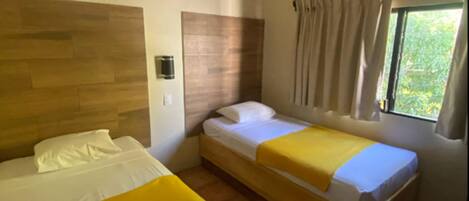 Une chambre d’hôtel avec deux lits, une fenêtre avec des rideaux, un appareil de climatisation et un luminaire fixé au mur.