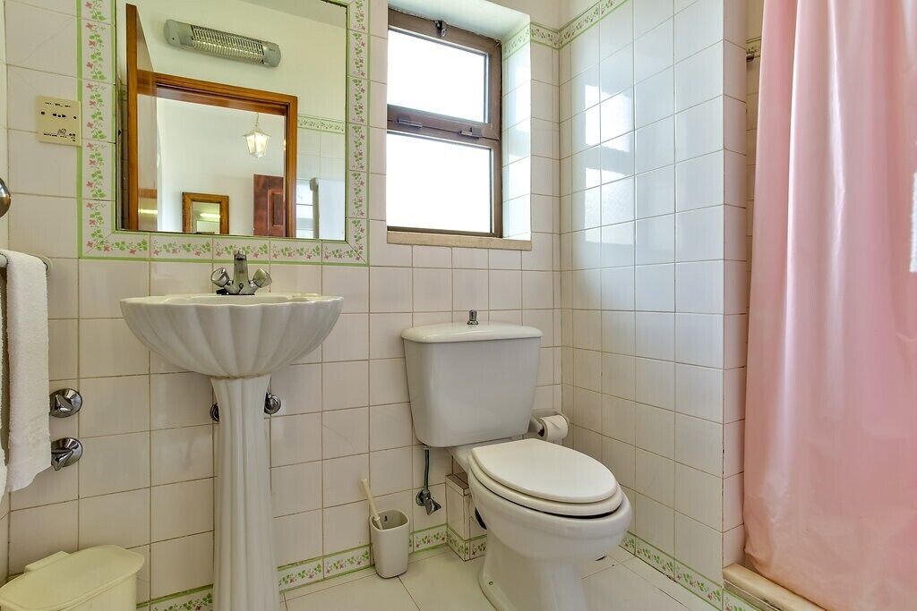 Une salle de bain avec un lavabo sur colonne, des toilettes et une fenêtre.