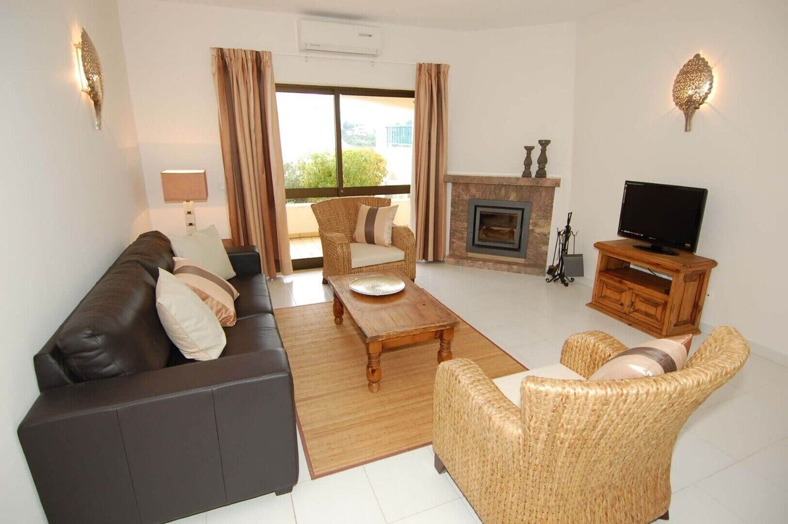 A living room with a sofa, chairs, a coffee table, a fireplace, and a television.