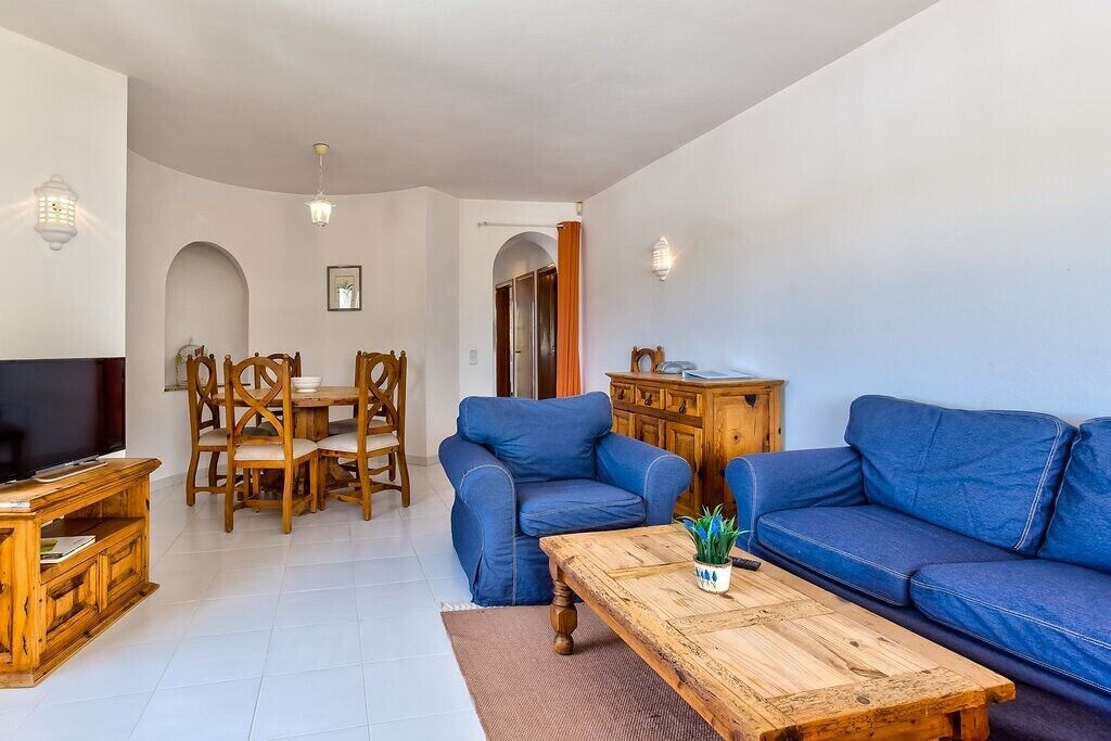 Un salon équipé d’un téléviseur, de meubles en bois, d’un canapé et d’un coin repas avec des chaises et une table.