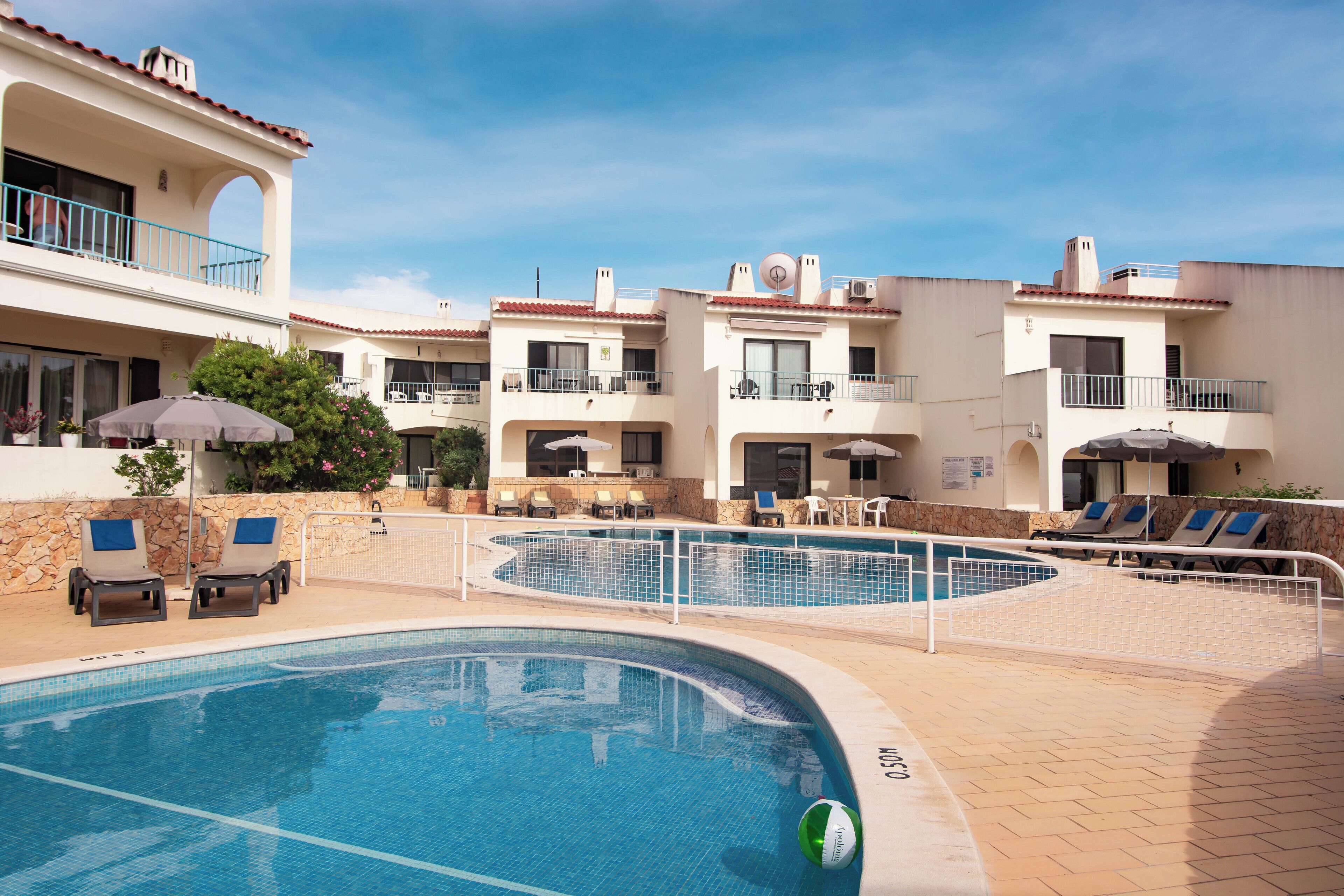 A swimming pool area with lounge chairs and a stone wall.