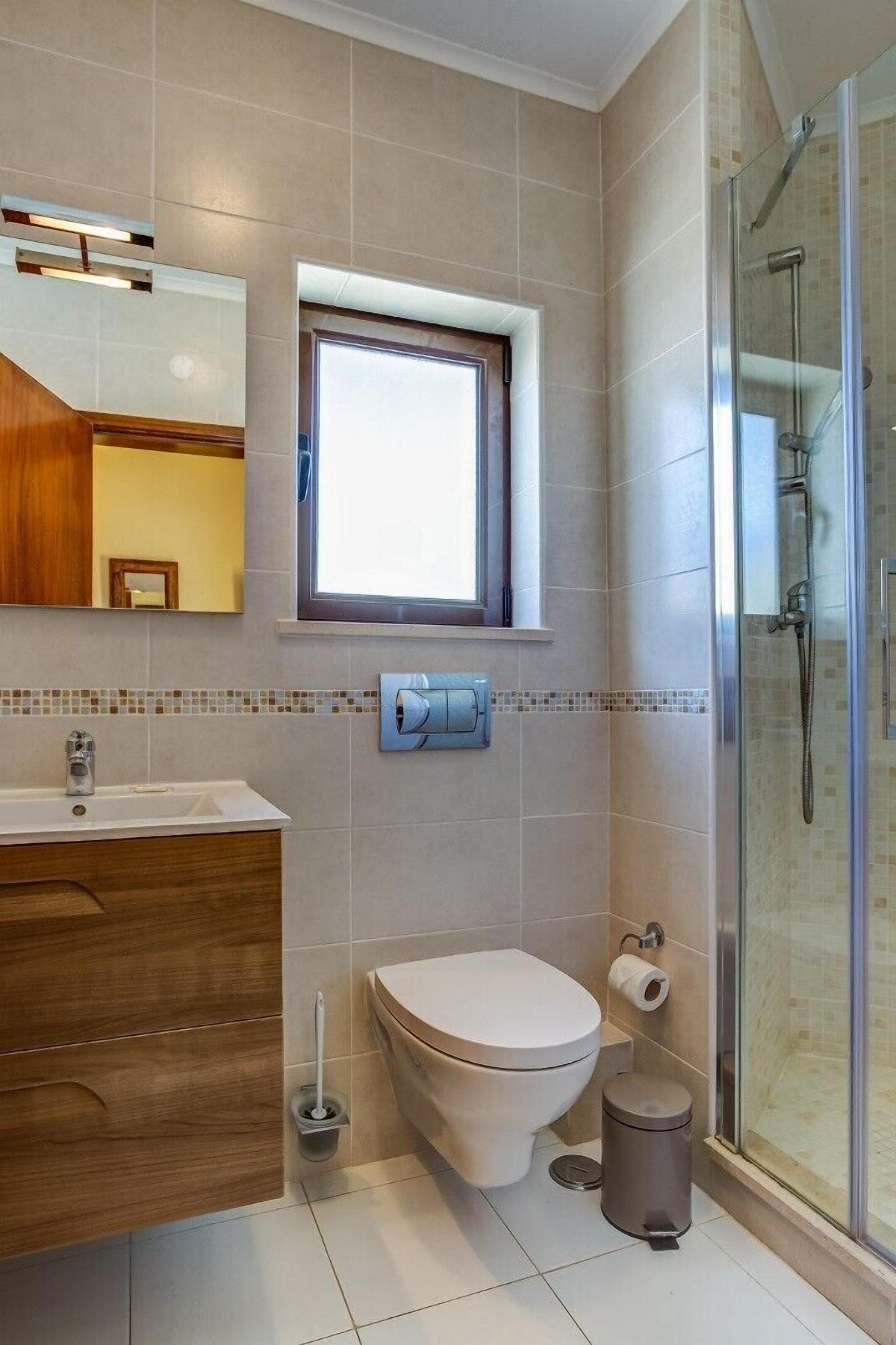Une salle de bain moderne équipée de toilettes, d’un bidet et d’une douche à parois de verre.