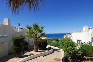 A coastal residential area with a clear view of the sea, a palm tree, and a paved pathway. - Monte Dourado Resort (Lagoa)