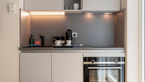 A modern kitchen with built-in appliances, a countertop with a coffee maker, and a window above the oven. - Pakat Suites (Vienna)