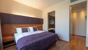 A modern bedroom with a large bed, wooden headboard, and a built-in bench. - Pakat Suites (Vienna)