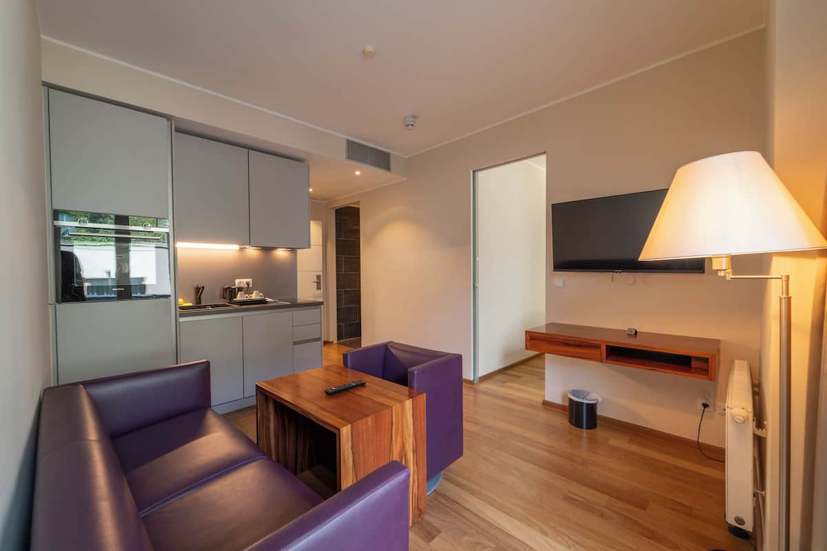 A modern living room with a sofa, a small wooden table, and a TV mounted on the wall.