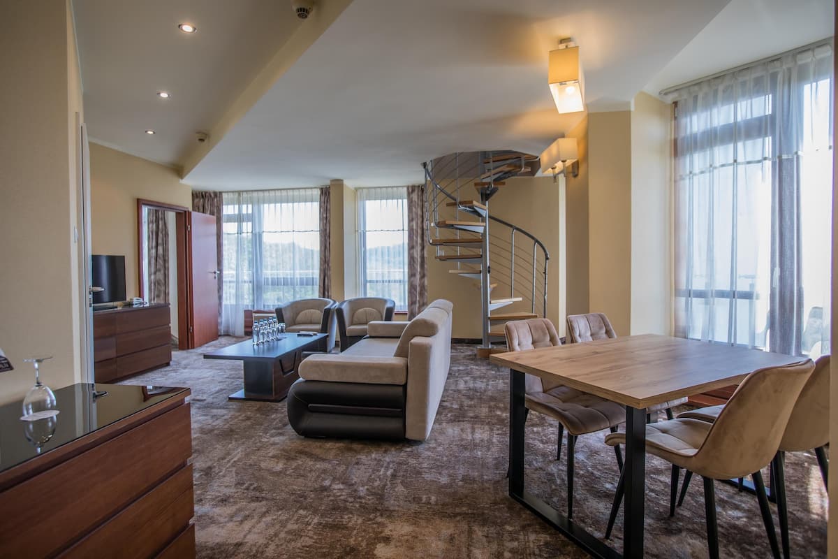A spacious living area with a sofa, a dining table, and a spiral staircase.