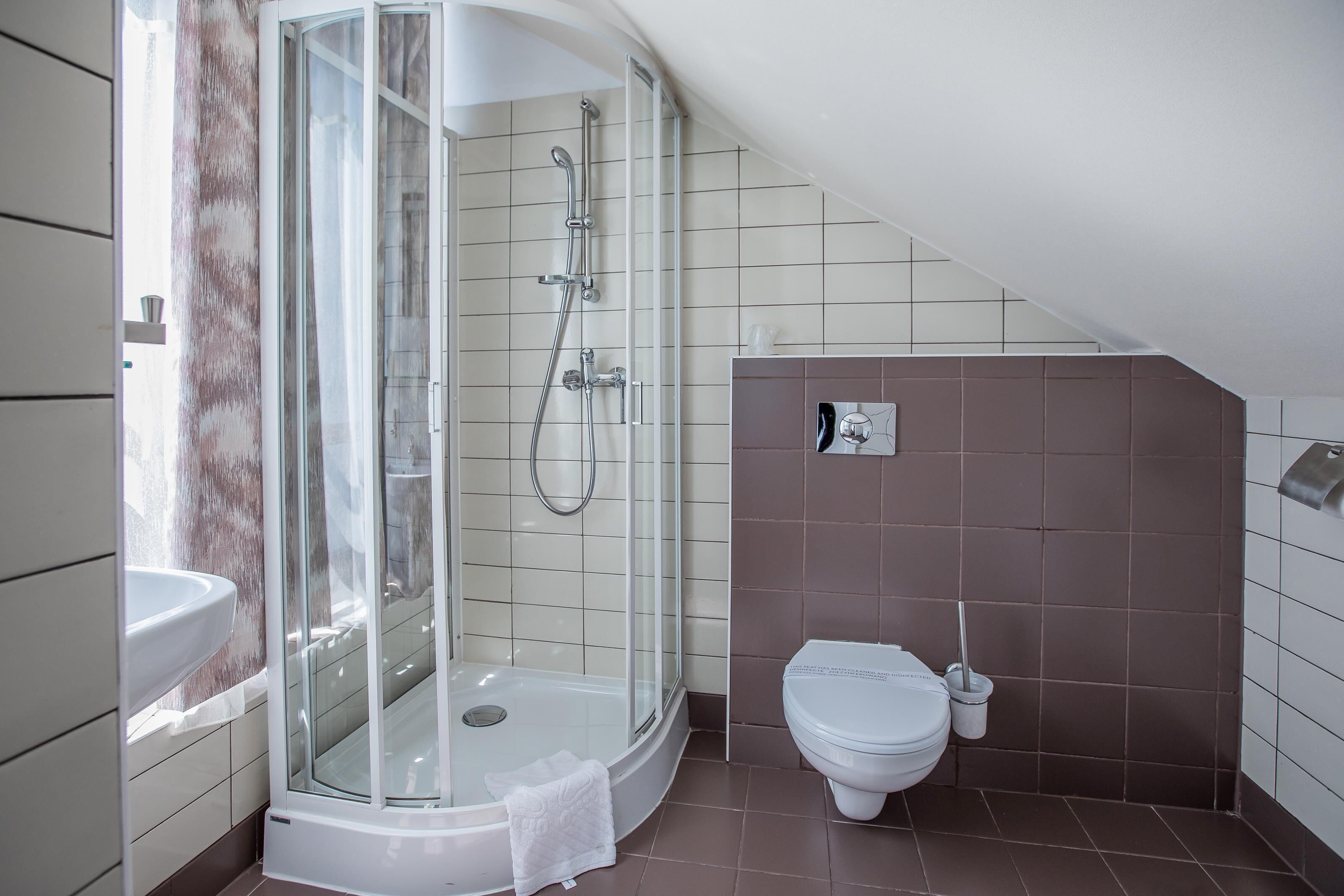 A modern bathroom with a glass-enclosed shower, a white sink, and a toilet.