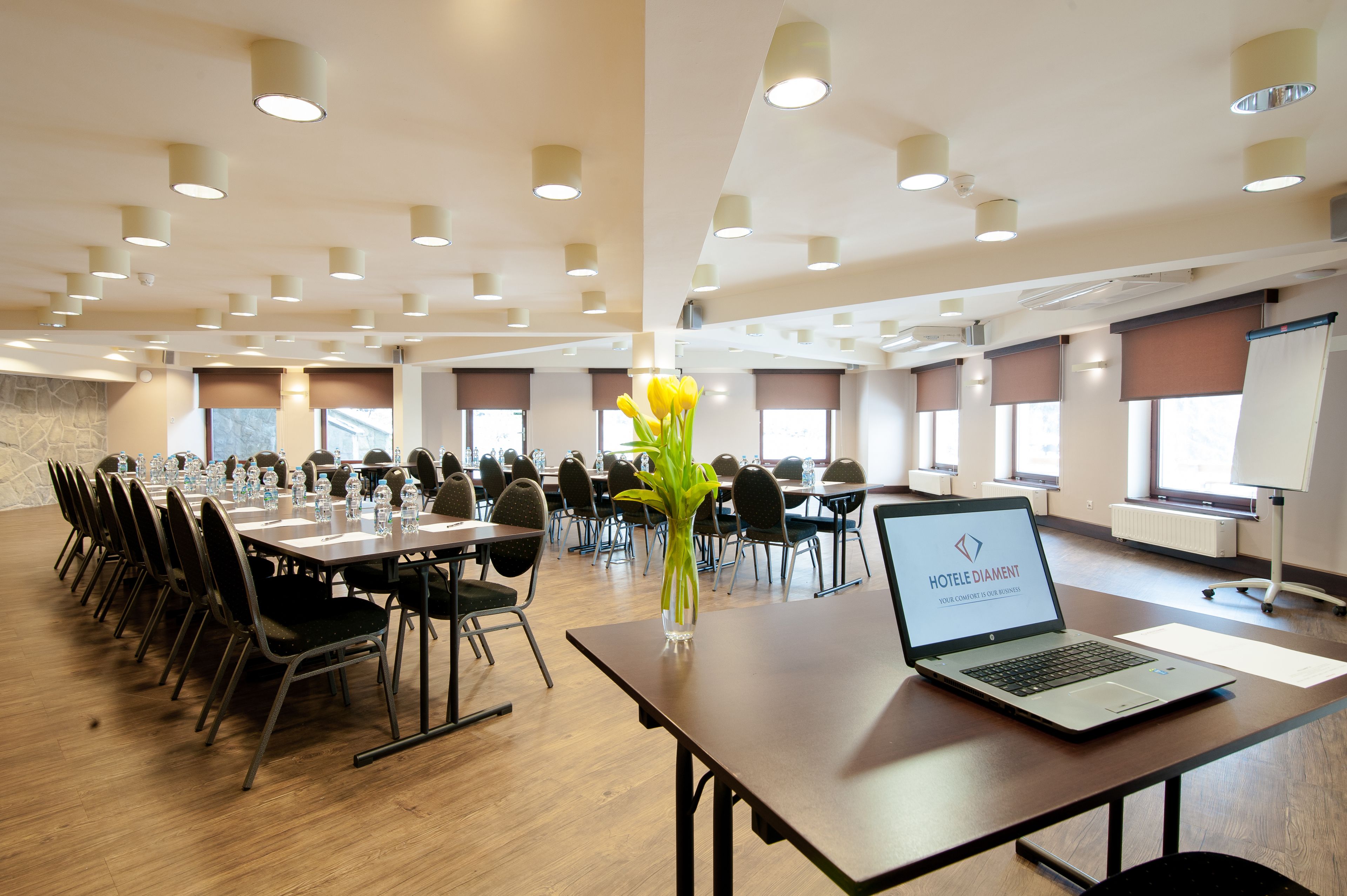 A conference room with multiple tables, chairs, and a laptop displaying 'HOTEL DIAMOND'.