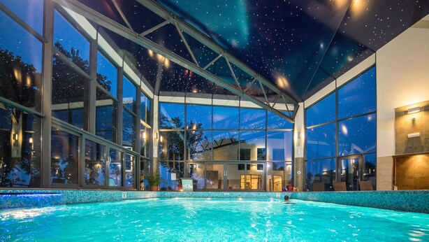 Une piscine dotée d’un plafond représentant un ciel étoilé, de grandes fenêtres et offrant une vue sur l’extérieur.