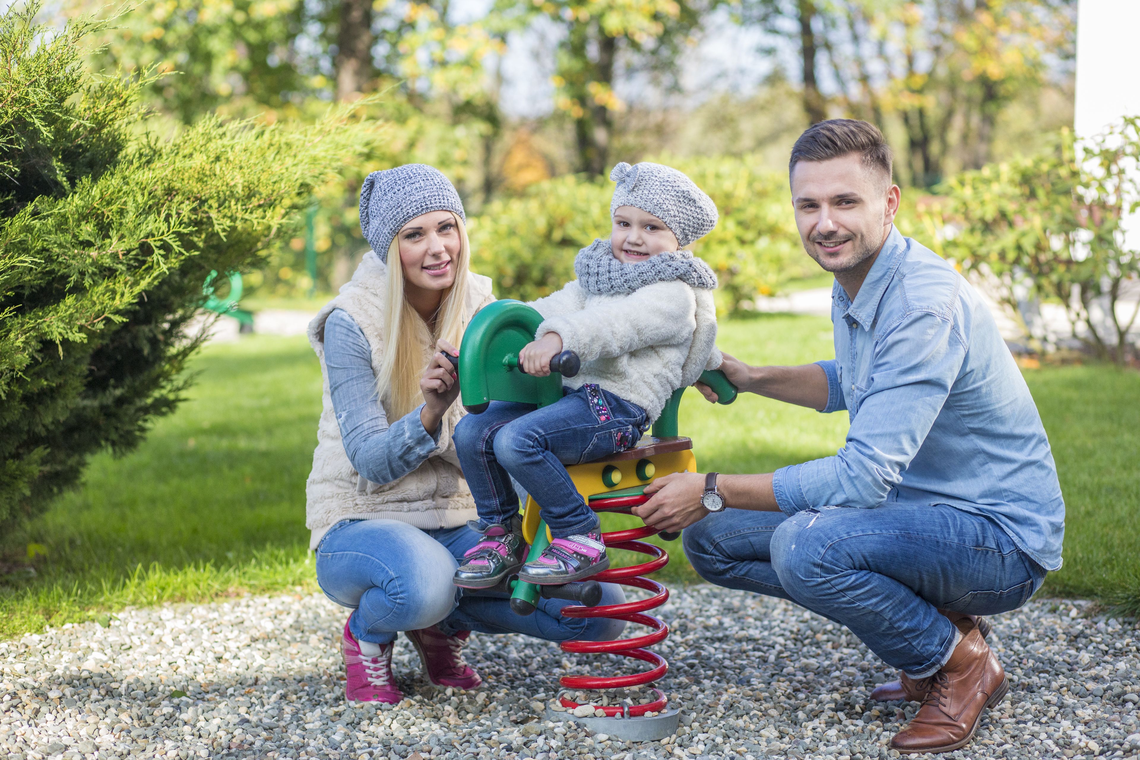 A family interacting with a playground equipment in a park.