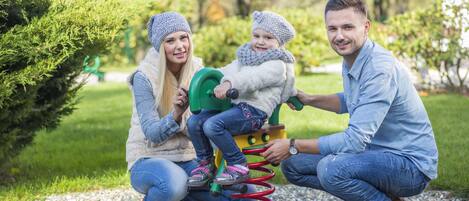A family interacting with a playground equipment in a park.