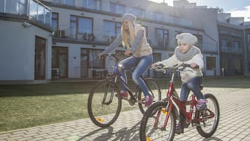 Deux personnes font du vélo sur une surface goudronnée, avec un bâtiment en arrière-plan.