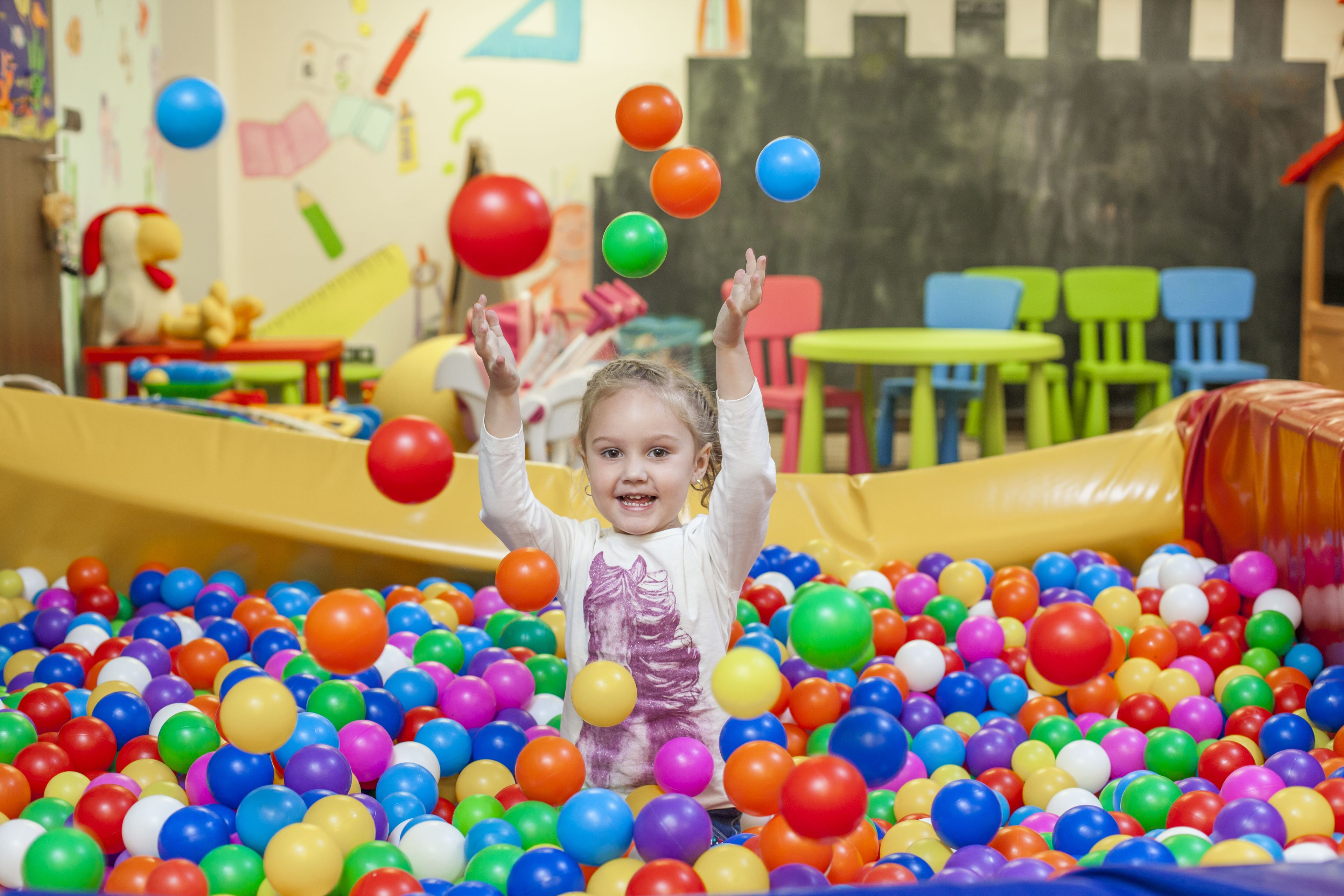 Un enfant joue dans une piscine à balles remplie de balles de couleurs vives.