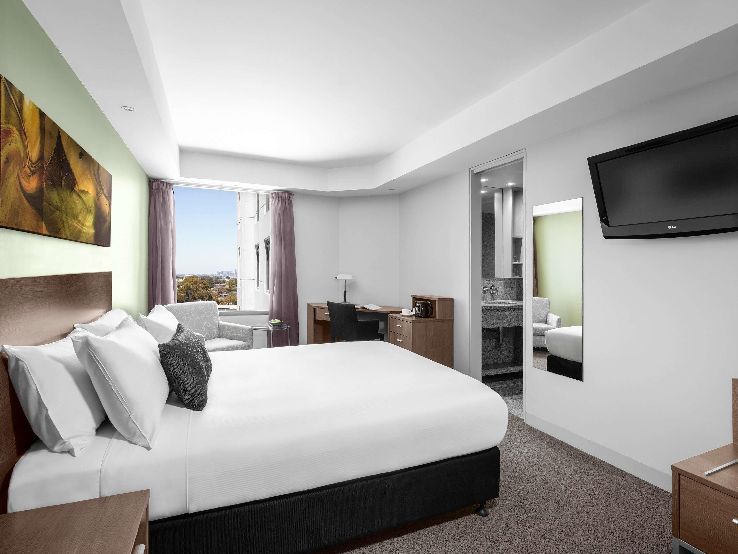 Een hotelkamer met een bed, bureau, stoel en een televisie.