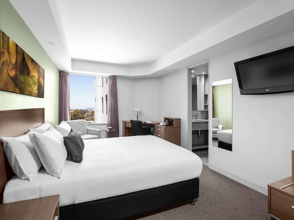 Una habitación de hotel con cama, escritorio, silla y televisor.
