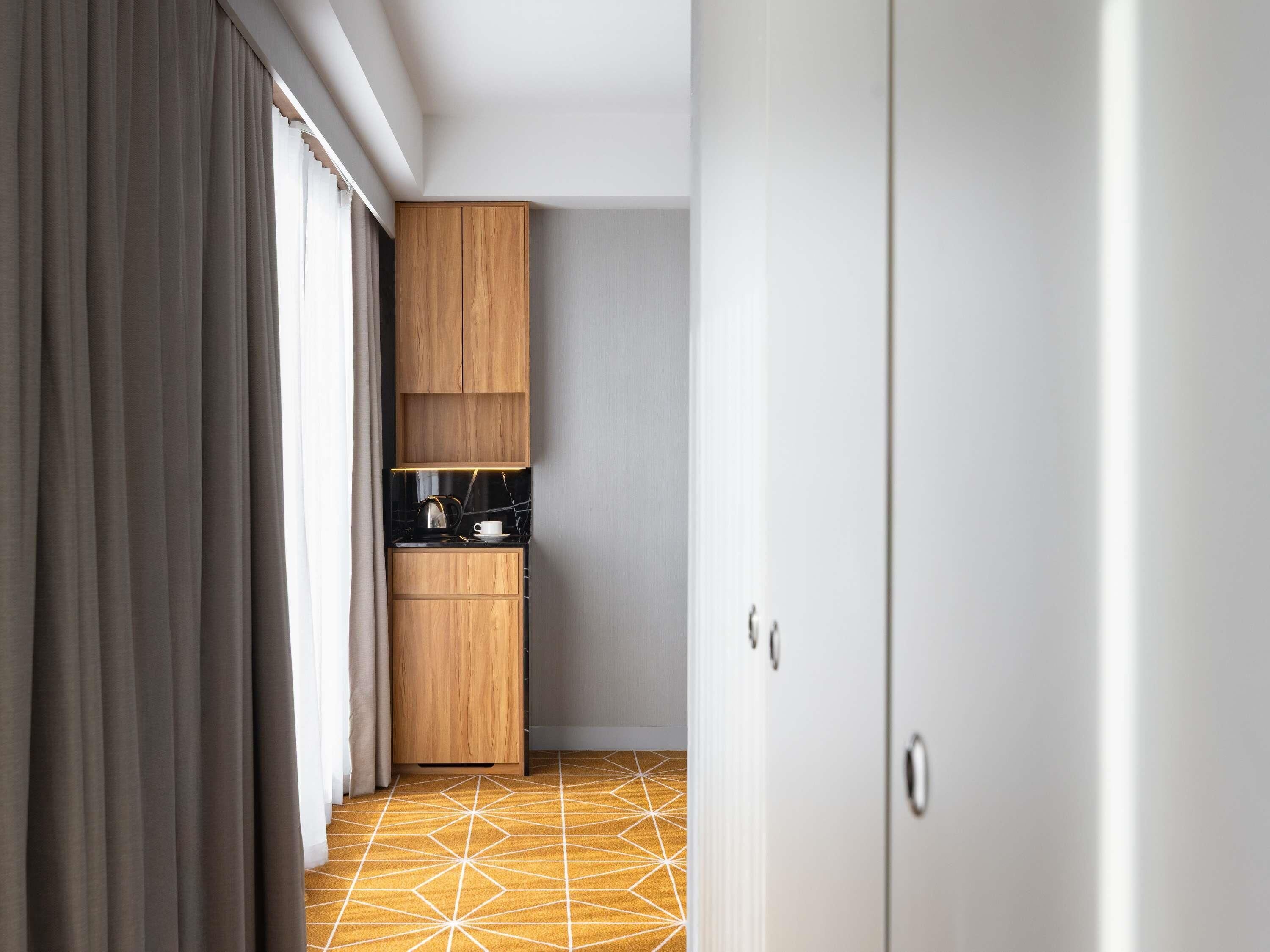 A modern kitchen with wooden cabinets, a countertop, and a patterned floor.