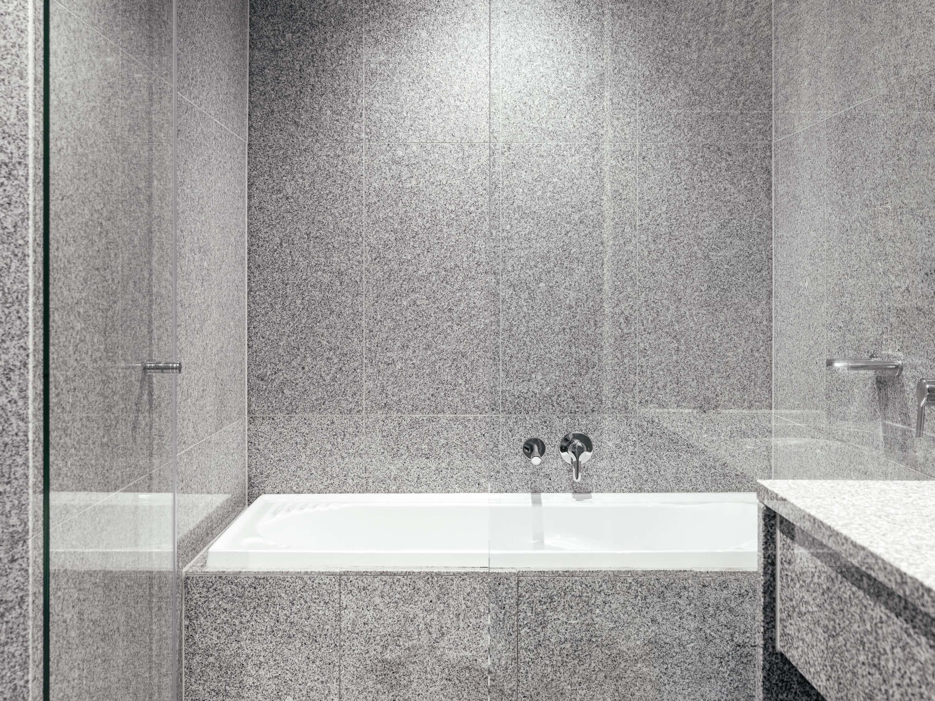 Une salle de bain moderne avec une baignoire rectangulaire, une cabine de douche en verre et un comptoir en granit.