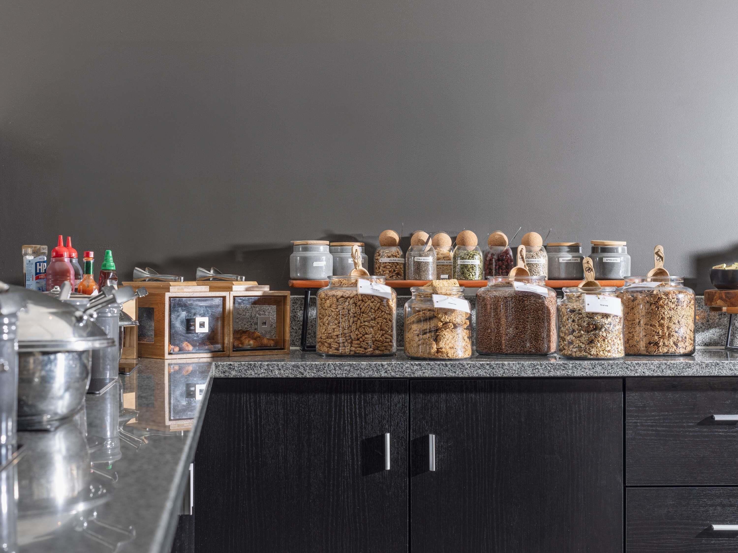 A kitchen counter with various food storage containers and condiments.