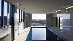 A modern indoor pool area with large windows offering a city view. - Mantra Melbourne Airport (Tullamarine)