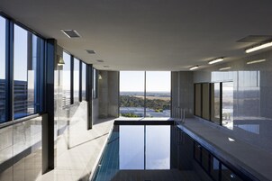 Un área de piscina interior moderna con amplios ventanales que ofrecen vistas a la ciudad.