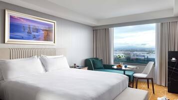 Une chambre d’hôtel avec un grand lit, une vue sur la ville, une table à manger et une chaise.