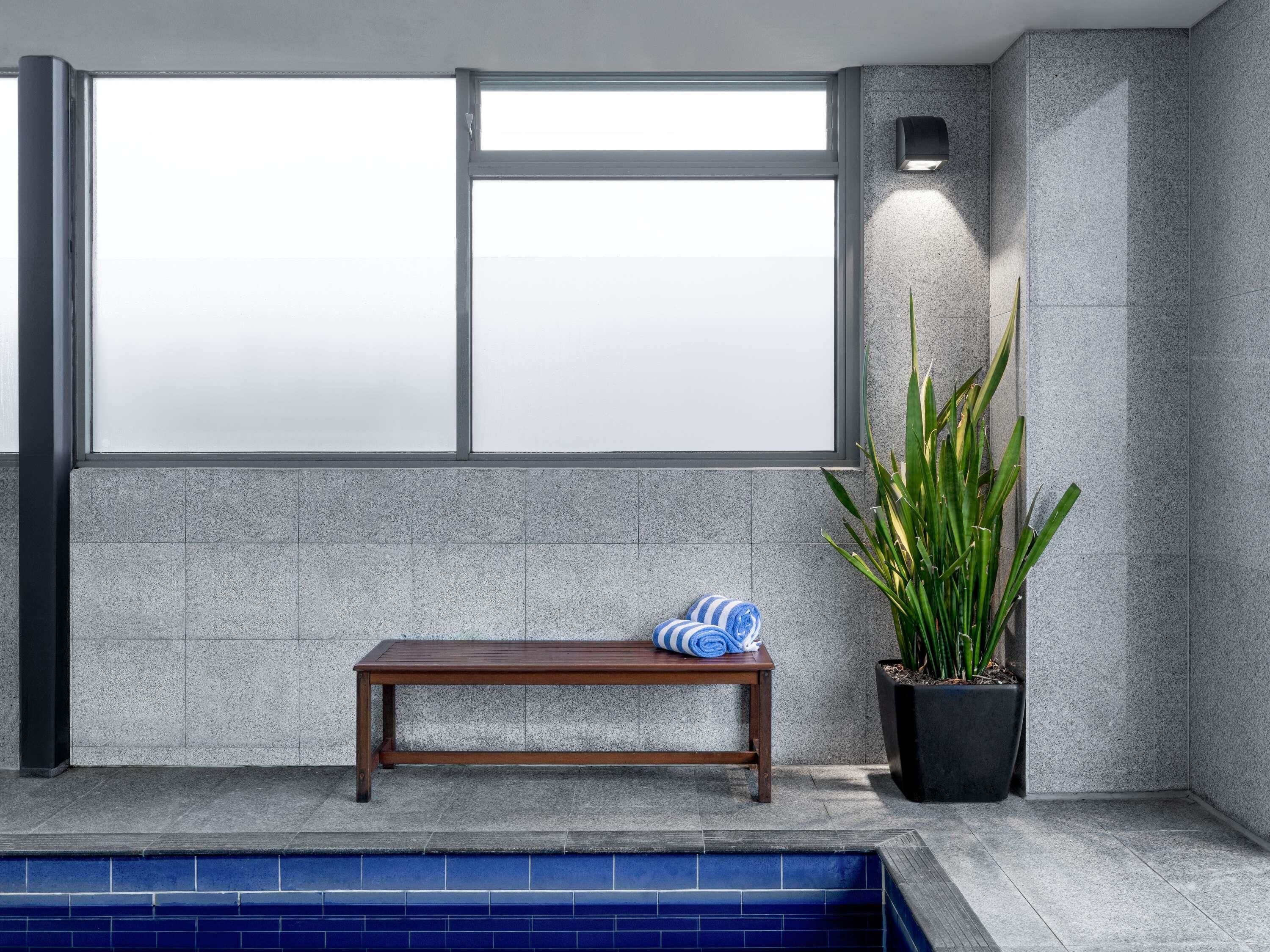 A spa area with a bench, a potted plant, and a large window.
