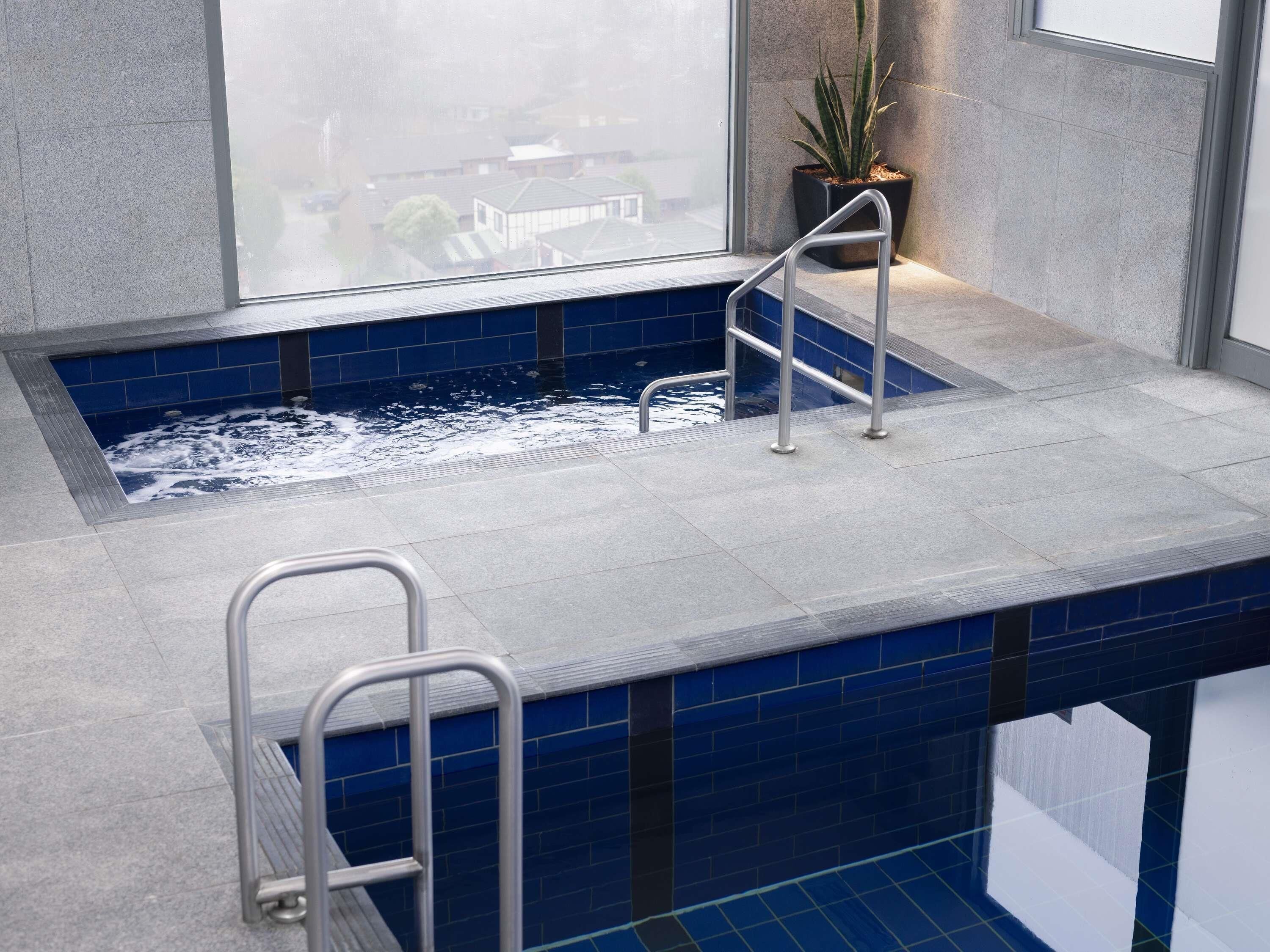 Un área de spa con un jacuzzi, barandillas metálicas y una planta en maceta.