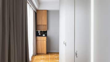 A narrow hallway with a geometric patterned floor, wooden cabinets, and a coffee maker on a counter.