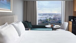 A hotel room with a large bed, a sofa, a dining table, and a view of the city. - Mantra Melbourne Airport (Tullamarine)