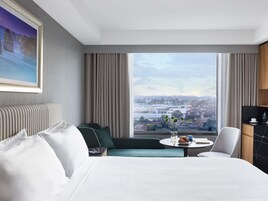 Habitación de hotel con una cama grande, un sofá, una mesa de comedor y vistas a la ciudad.