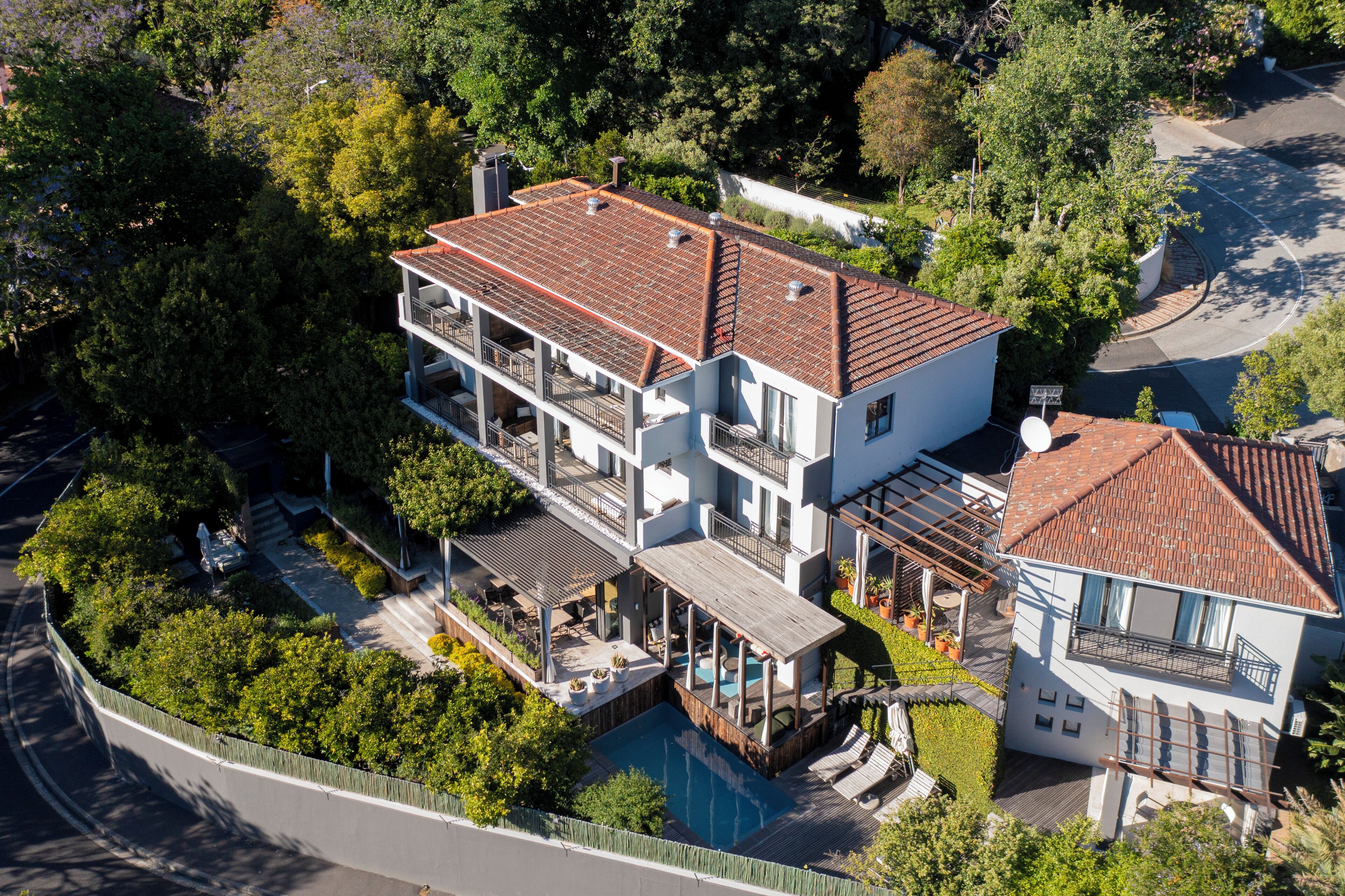 A multi-story house with a swimming pool, balconies, and a garden.