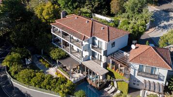 A multi-story house with a swimming pool, balconies, and a garden.